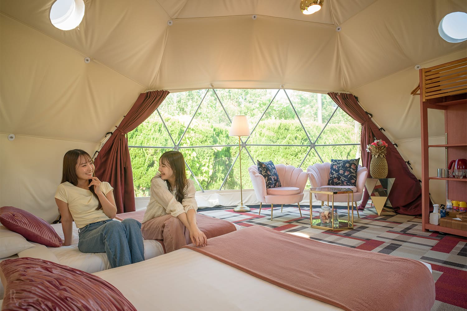 Photo of women relaxing on beds inside a dome tent